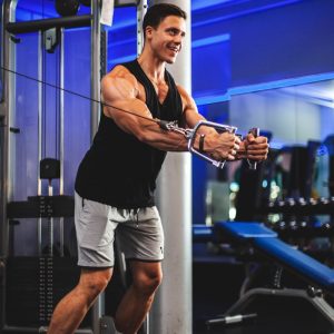 man in black tank top and gray shorts holding black smartphone